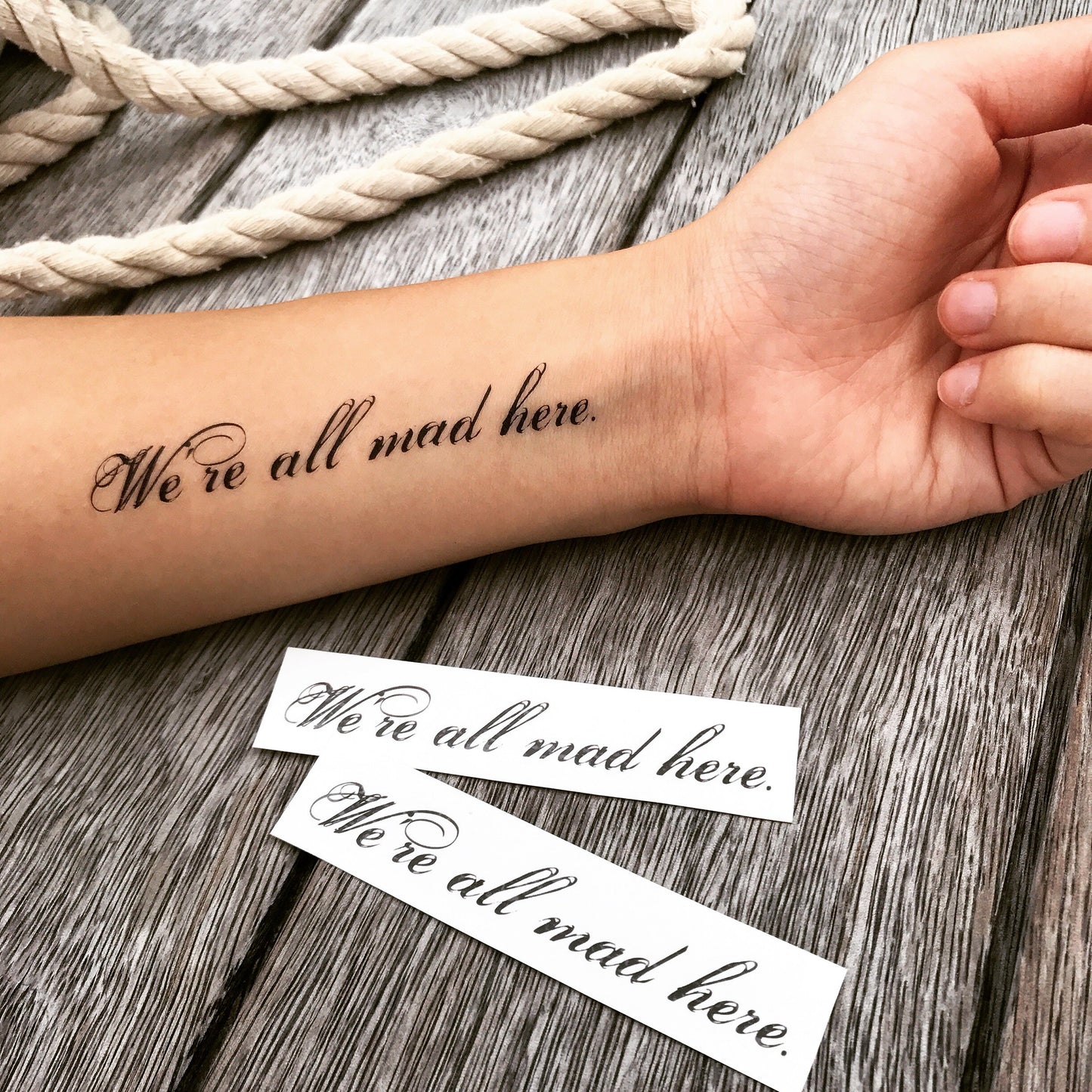 fake small we are all mad here lettering temporary tattoo sticker design idea on forearm