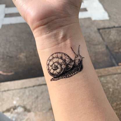 fake small snail slug animal temporary tattoo sticker design idea on wrist