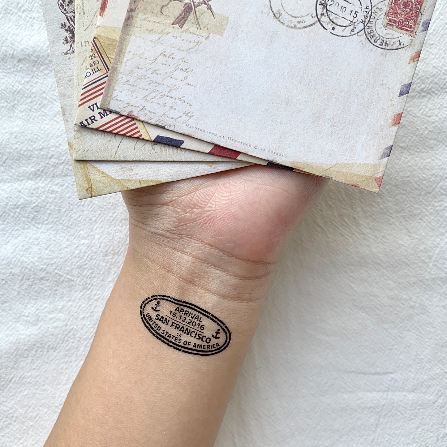 fake small passport stamp color temporary tattoo sticker design idea on wrist