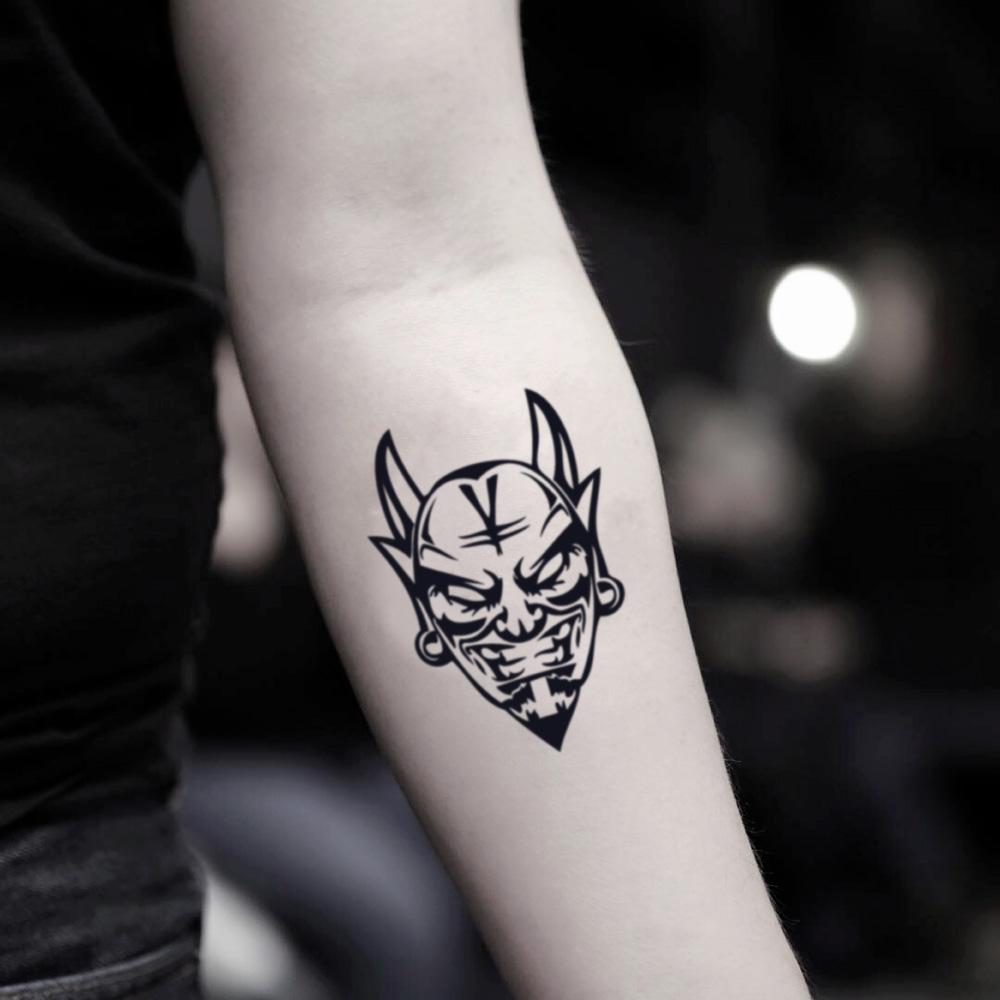 fake small black devil head demon face kabuki oni mask illustrative temporary tattoo sticker design idea on inner arm
