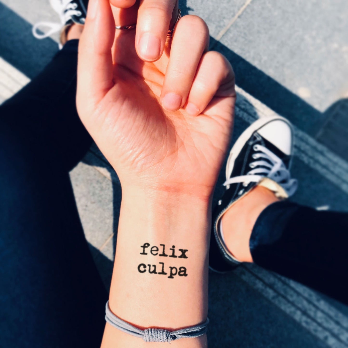 fake small felix culpa latin lettering temporary tattoo sticker design idea on wrist