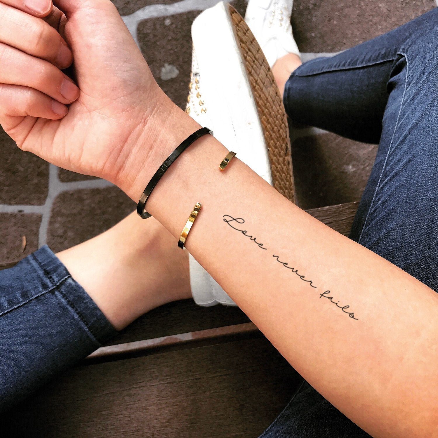 fake small love never fails lettering temporary tattoo sticker design idea on forearm