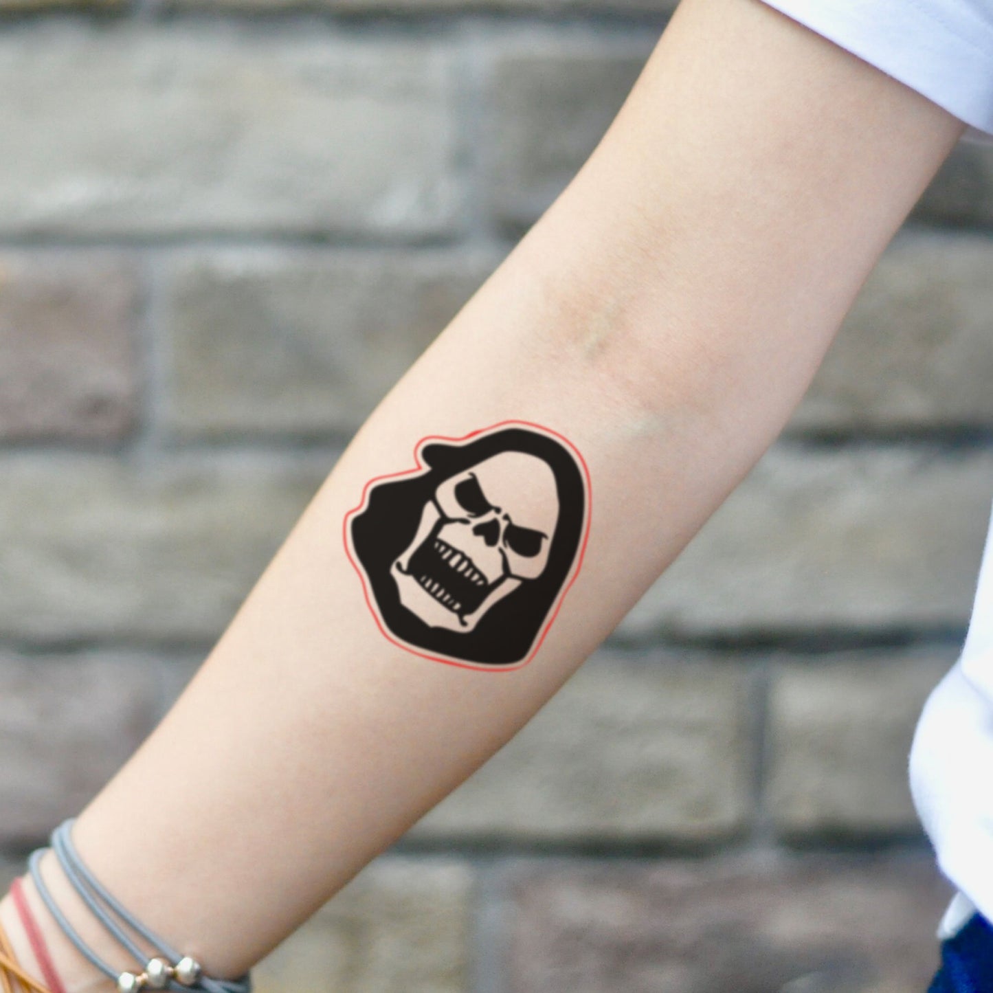 fake small skeletor skull head minimalist temporary tattoo sticker design idea on inner arm