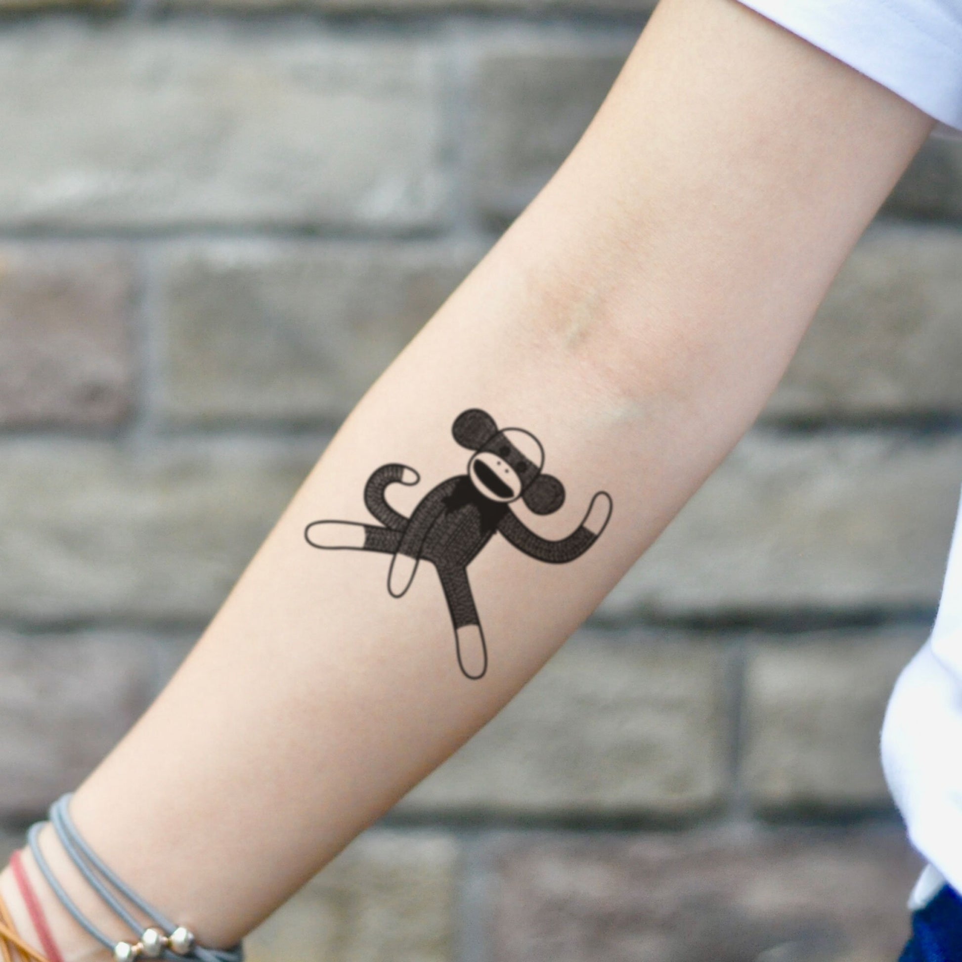fake small sock monkey illustrative temporary tattoo sticker design idea on inner arm