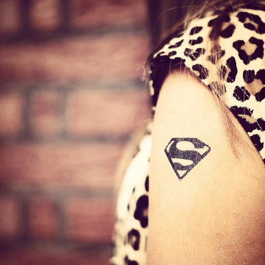 fake small superman superwoman supergirl logo cartoon temporary tattoo sticker design idea on upper arm