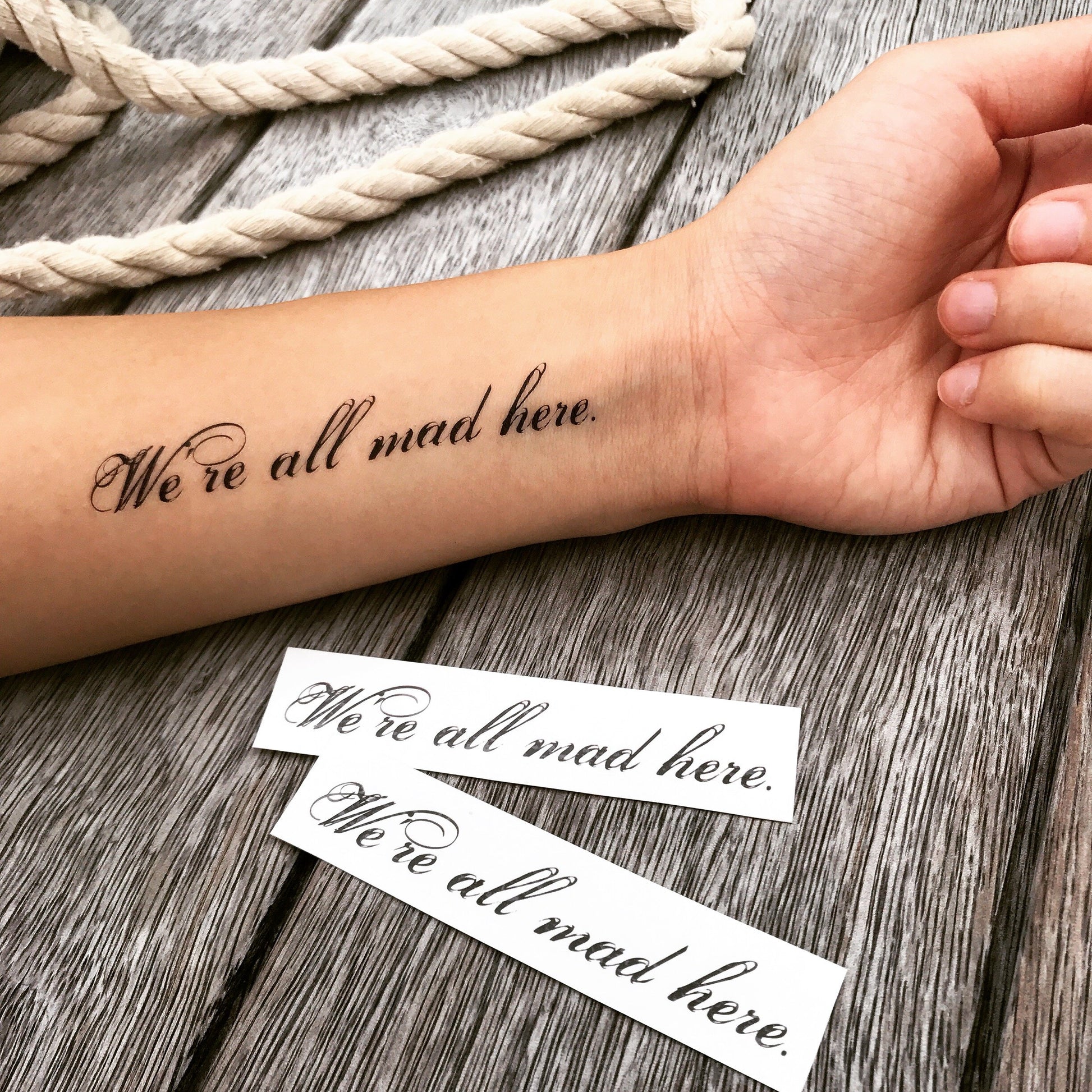 fake small we are all mad here lettering temporary tattoo sticker design idea on forearm